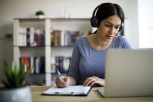une femme devant un ordinateur avec un casque sur les oreilles